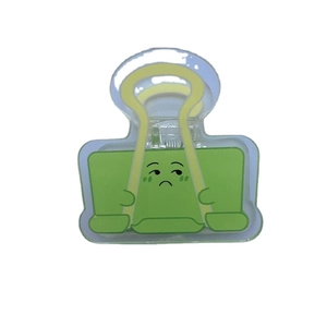 Clip per appunti minimalista in acrilico verde con un simpatico viso triste a fumetti