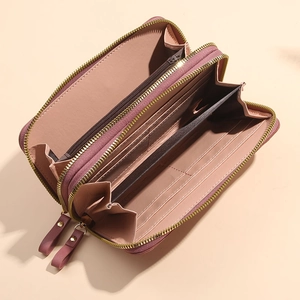Rose pink long wallet with dual zippers and multi-card slots shown open on beige background