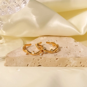 Detailed view of gold wave ring with white pearls and zircons on a stone background