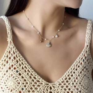 Détail d'un collier pendentif étoile de mer et coquillage doré avec perles sur un mannequin