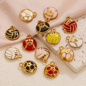 Enamel sports ball pendants including volleyball and football on a pink satin surface