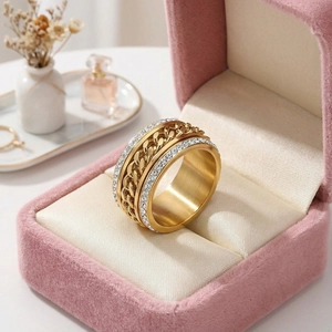 Vue macro d'une bague chaîne dorée avec strass latéraux dans un écrin en velours rose