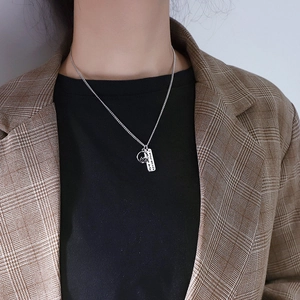 Silver dual pendant necklace with engraved French tag and hollow ring on a model