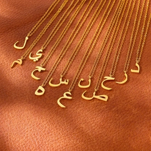 Detailed view of multiple golden Arabic script pendants on a luxury leather surface