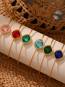 Detail of six colorful square-cut gemstone open bangles on a white display stand