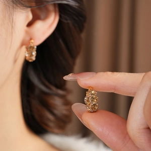 Detail von vergoldetem Creolen-Ohrring mit bernsteinfarbenem Stein und Pavé-Diamanten
