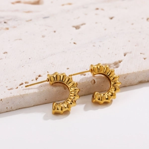 Close-up of C-shaped 18K gold plated earrings featuring a pleated wavy metal texture