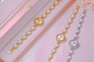 Close-up of three luxury quartz watches with pearl bracelets in gold and silver finishes