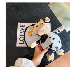 Close-up of a cute cow plush bag with black and white spots and adjustable strap