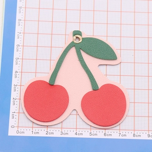 Close-up of pink and red leather cherry keychain charm on a scale measuring mat