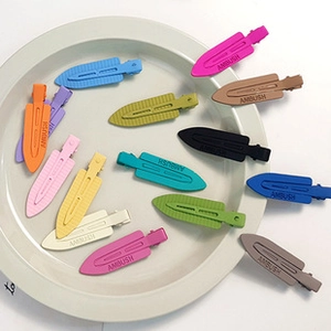 Detail showing colorful matte hair clips in a ceramic dish with logo engraving