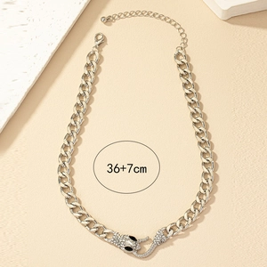 Detail showing the snake head buckle with white rhinestones on the gold chain necklace