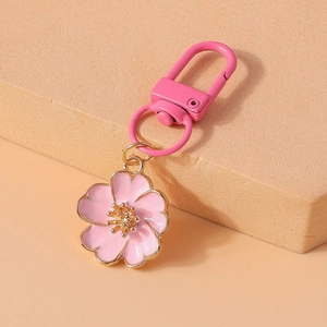 Detail of pink enamel flower keychain with golden edges and matching pink lobster clasp