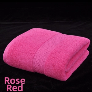Close-up of rose red cotton bath towel with woven decorative border on black background