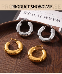 Detailed shot of large chunky gold and silver hollow hoop earrings on a wooden tray