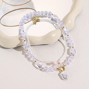Detail of double-layer baroque pearl necklace with floral pendant on a cream wavy tray