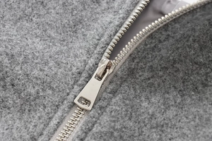 Macro shot of silver metal zipper on soft grey plush bomber jacket fabric