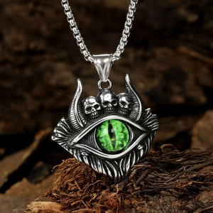 Macro detail of gothic pendant with green eye and skulls on a vintage wood texture