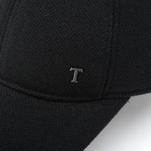 Macro detail of black textured baseball cap with a matte silver metal letter T logo