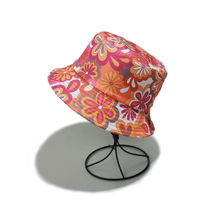 Detail of retro hippie floral bucket hat with colorful daisy patterns on a metal stand