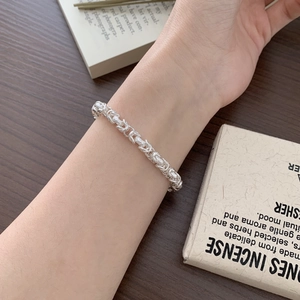 Minimalist 925 sterling silver hand-woven bracelet with geometric texture on wood surface