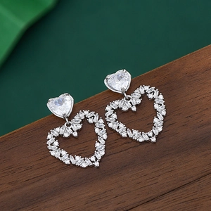 Macro detail of elegant S925 silver heart earrings featuring double zircon stone inlay
