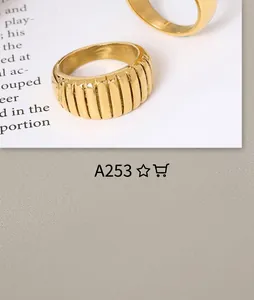 Macro view of gold plated croissant ring with pleated texture on white book background