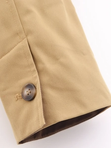 Détail de la manchette en coton sergé kaki avec un bouton en résine brun foncé élégant