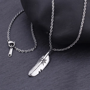 Macro detail of retro steel feather pendant with intricate sunburst texture on O-chain