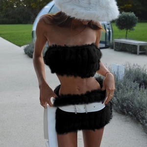 Detail eines schwarzen Plüsch-Bandeau-Tops und Minirocks an Model im modernen Garten