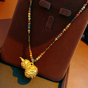 Macro shot of gold hollow gourd pendant with turquoise and agate gemstone beads necklace