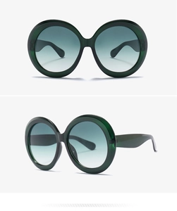 Macro shot of oversized round sunglasses with dark green frames and gradient lenses