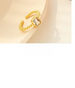 Detail of a gold adjustable ring featuring a beaded band and a rectangular clear zircon stone