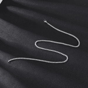 Close-up of a 3.5mm silver stainless steel box chain necklace on dark fabric