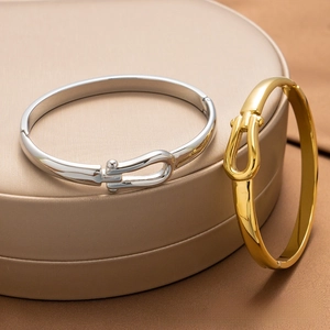 Close-up of gold and silver U-shape horseshoe buckle bangles with mirror finish