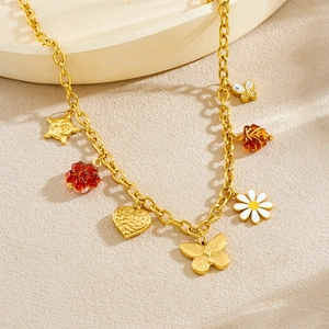 Gold stainless steel necklace with daisy, butterfly, and heart charms on a beige surface