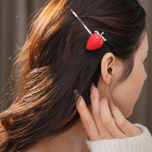 Dettaglio di un fermaglio per capelli a fragola in resina rossa indossato da una modella