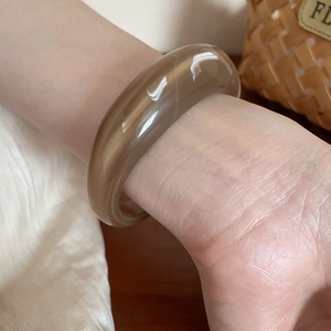 Detail of amber acrylic bangle with white marble texture on wrinkled fabric background