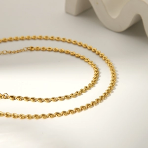 Detailed macro view of interlocking golden heart-shaped links on the stainless steel necklace