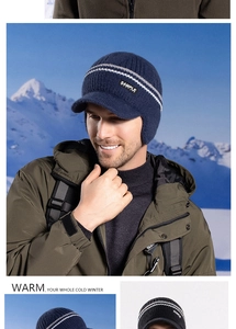 Men's navy knit winter hat with earflaps and visor shown in outdoor snowy mountains