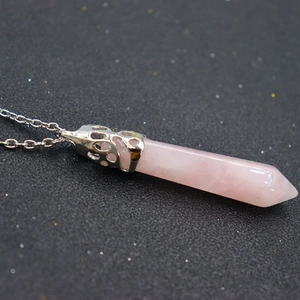 Macro shot of rose quartz hexagonal pendant with silver hollow filigree and metal chain
