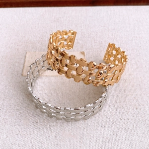 Detailed view of gold and silver triple-layered open cuff bracelets on linen fabric