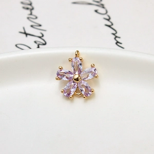 Macro view of purple zircon flower pendant with gold plating on white ceramic