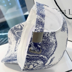 White canvas baseball cap with blue floral pattern and adjustable silver metal buckle