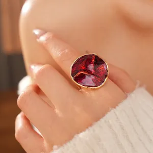 Vintage red enamel round ring with gold metallic edges worn by a model on a soft background
