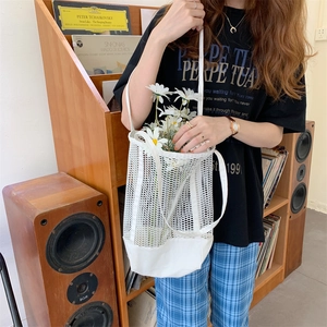 Detail of white mesh tote bag with reinforced canvas bottom held in a cozy home setting