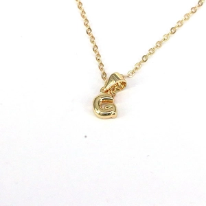 Detailed close-up of a gold-plated necklace featuring a minimalist letter G pendant