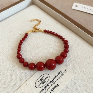 Détail du bracelet en perles dégradé rouge avec fermoir ajustable en métal doré