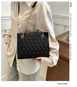 Detailed view of black quilted faux leather tote bag with elegant gold chain strap
