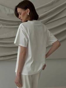 Detail of white cotton T-shirt showing soft fabric texture and side drape on a model